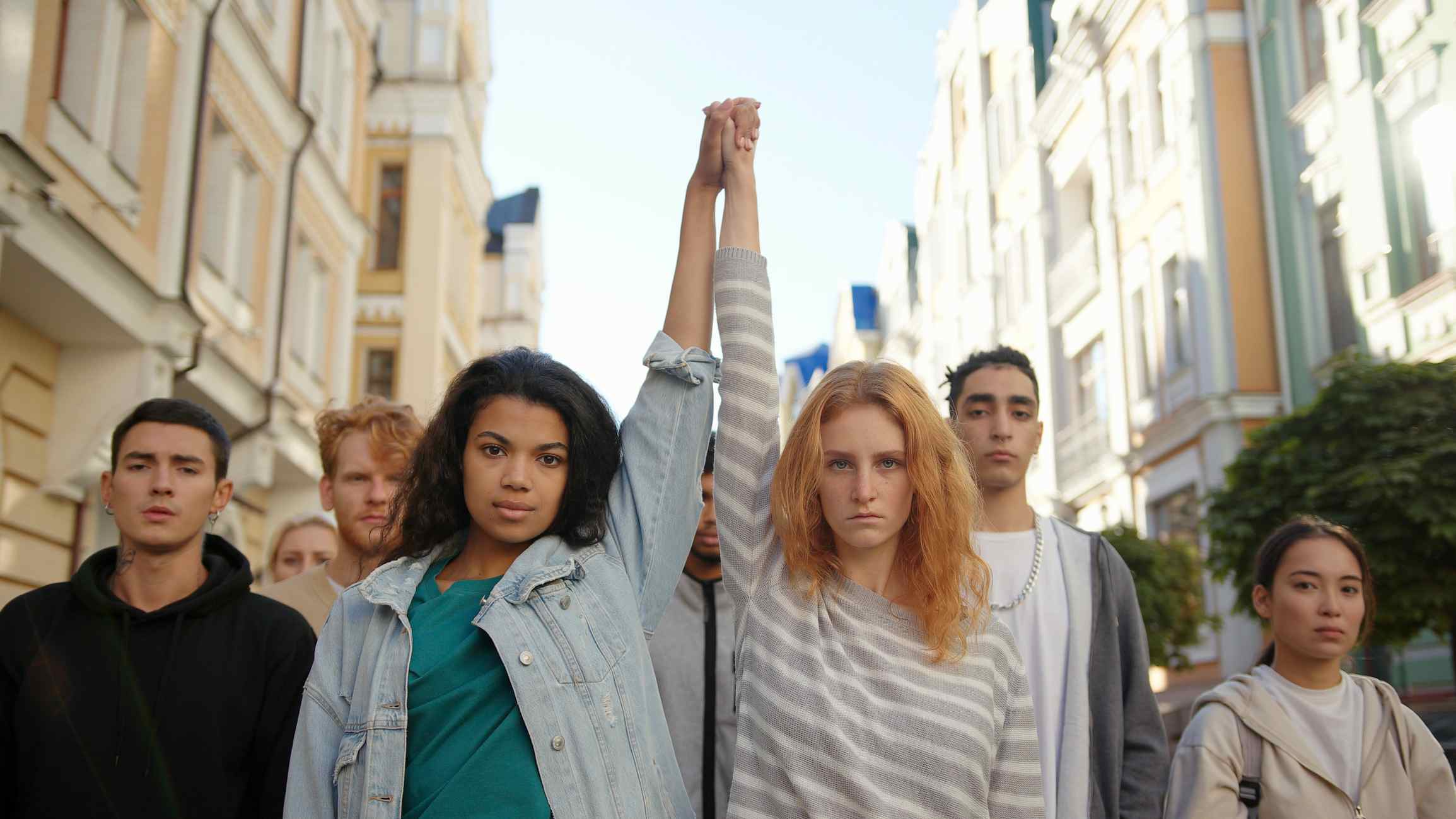 A diverse group of young people raising their fists in solidarity on a city street.