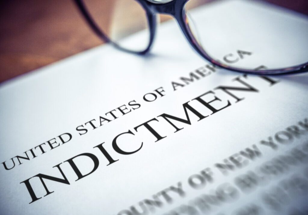 Close-up of an indictment document with glasses in the background.