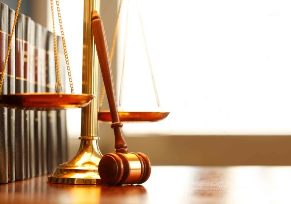 A judge's gavel and scales of justice on a wooden table.